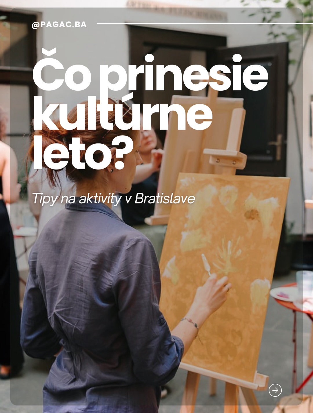 Žena maľuje na stojane v ateliéri, v pozadí ďalší účastníci a plátna.